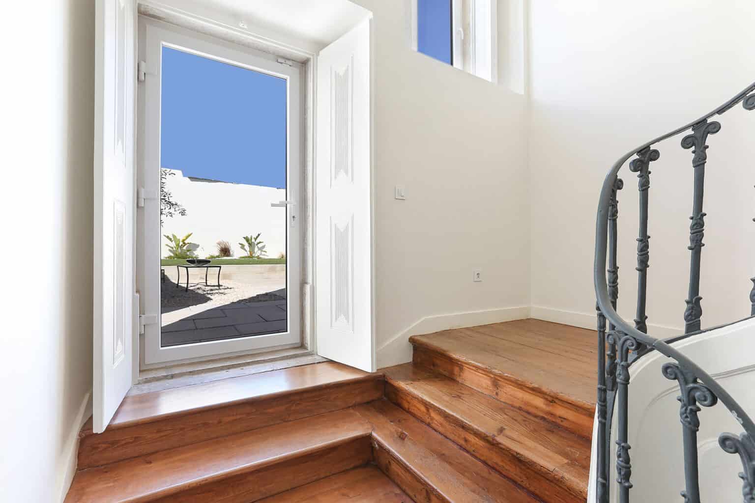 Charming villa entrance with wooden stairs and a view of the outdoor patio area.