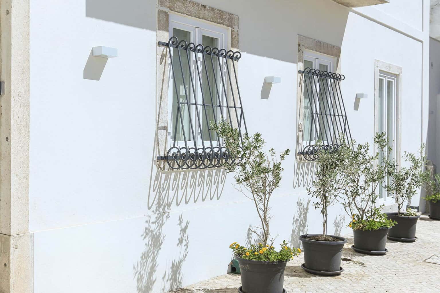 Elegant villa exterior with decorative window grilles and potted plants in Ajuda.