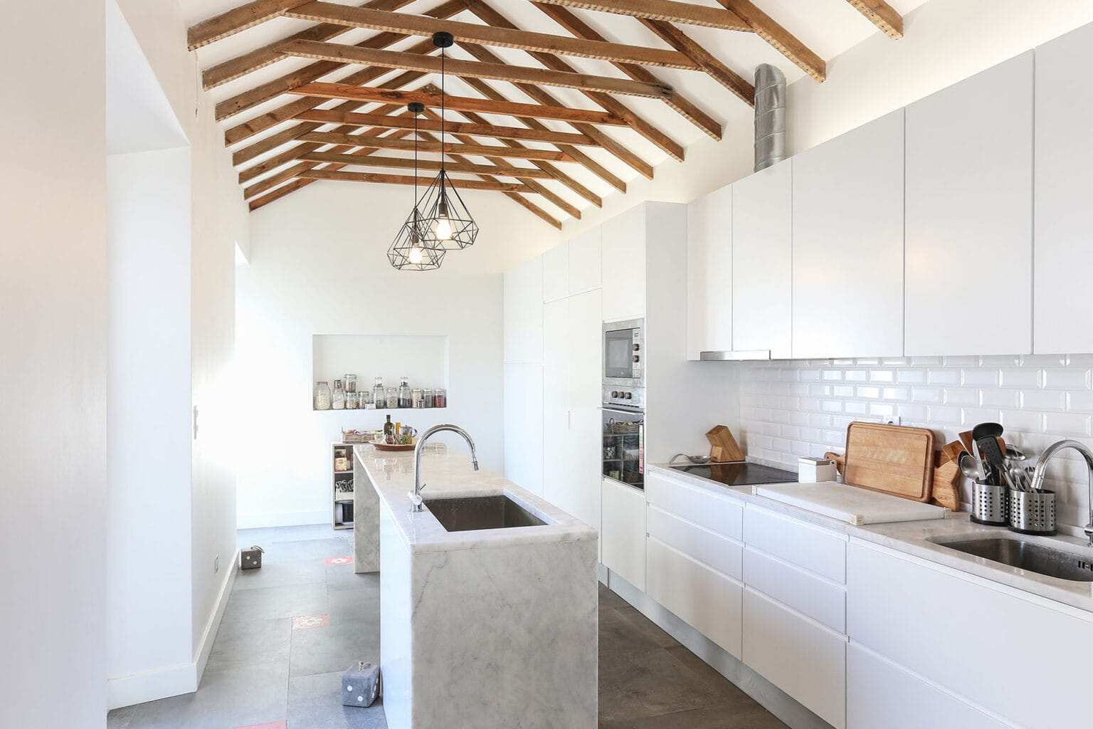 Elegant kitchen with white cabinets, marble island, and natural light.
