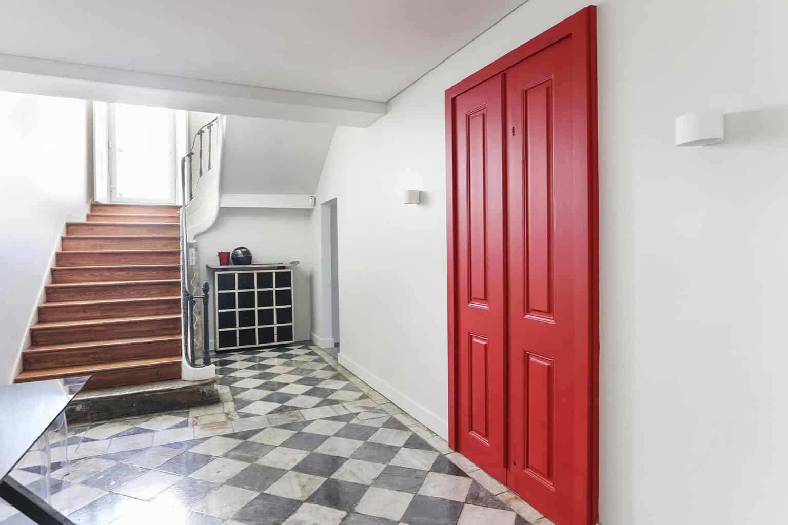 Bright interior hallway with stylish red door and staircase.